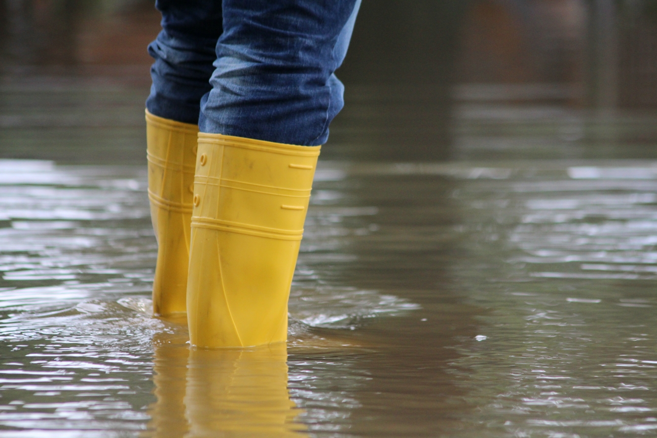 Gelbe STiefel in einem von Hochwasser überfluteten Fluss, was zeigt weshalb jetzt gegen Hitze gehandelt werden muss